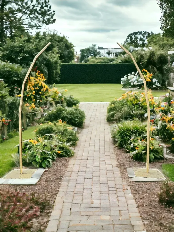 Modern gold metal wedding arch frames a garden pathway surrounded by vibrant flowers and greenery at an outdoor Atlanta venue.