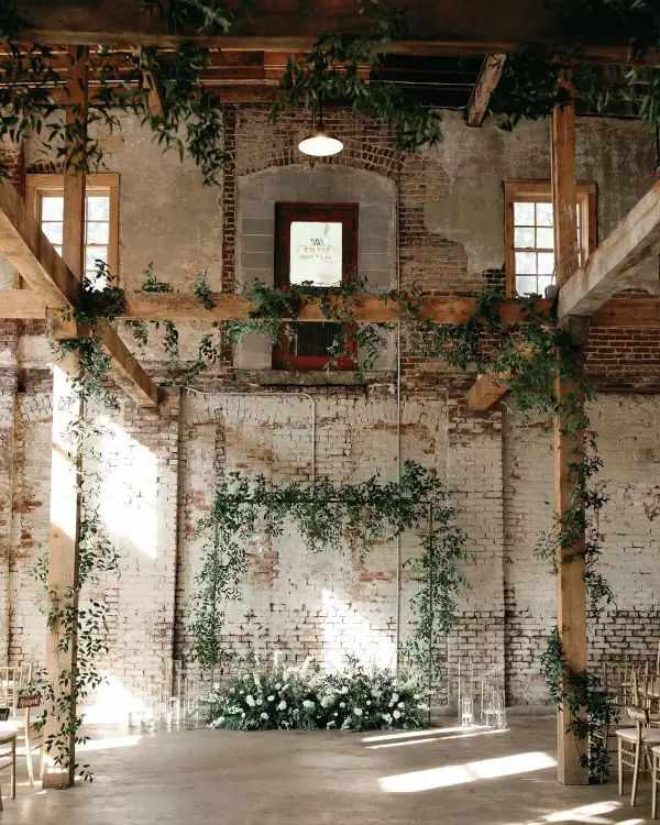 Minimal greenery wedding arch in an industrial brick and timber venue.