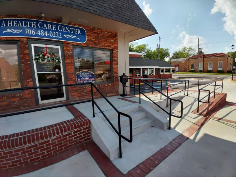 Black steel handrails along steps and an accessibility ramp outside a brick commercial building entrance
